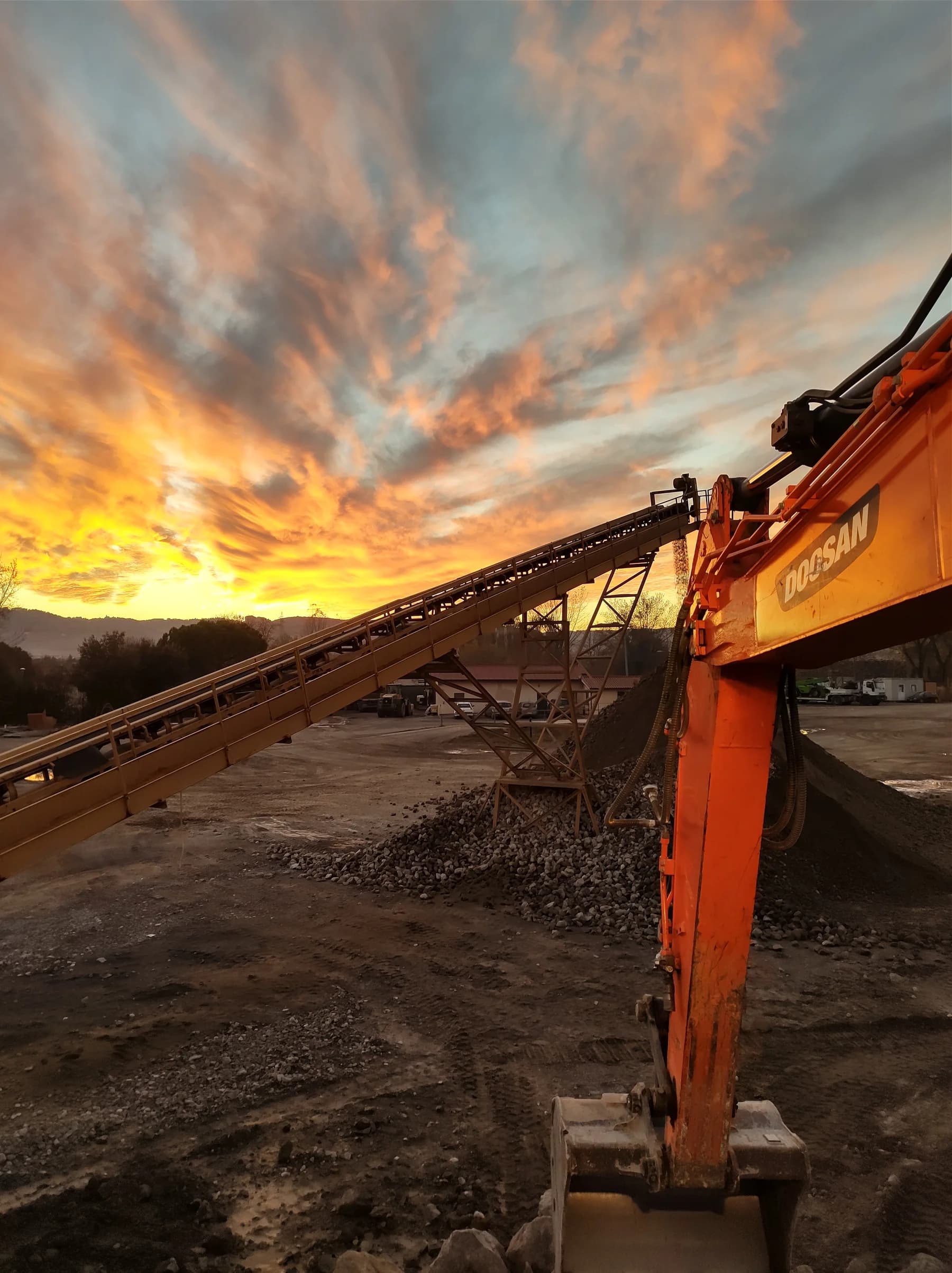 Escavatore Edilcave al lavoro nell’impianto al tramonto